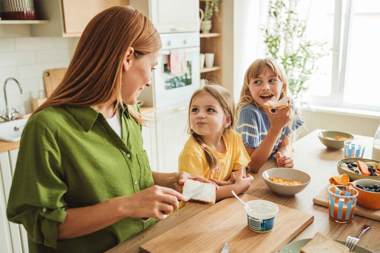 Mother preparing healthy snack for her daughters in the afternoon after school